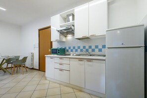 Eine moderne Küche mit weißen Schränken, einer eingebauten Mikrowelle und einem Kühlschrank.