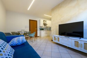 Ein modernes Wohnzimmer mit einer Couch, einem Flachbildfernseher und einem Essbereich mit Stühlen und einem Tisch.