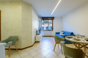 A modern living room with a dining area, a blue sofa, and a TV on a white stand. - A charming and welcoming 48-square-meter apartment, perfect for two people, located on the first floor of a building without an elevator.The property is situated in a central area of ​​Pesaro: Piazza del Popolo, Rocca Costanza, and Palazzo Mosca are  (Pesaro)