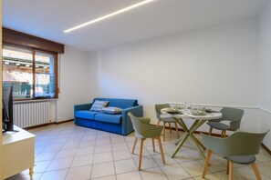 A modern living room with a blue sofa, a dining table with chairs, and a TV on a stand. - A charming and welcoming 48-square-meter apartment, perfect for two people, located on the first floor of a building without an elevator.The property is situated in a central area of ​​Pesaro: Piazza del Popolo, Rocca Costanza, and Palazzo Mosca are  (Pesaro)