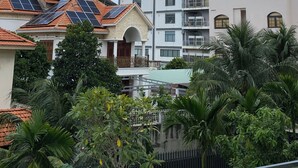 A multi-story building with balconies, a construction crane, and solar panels on nearby buildings. - DaNy Living Thao Dien by DNM Hospitality (Ho Chi Minh City)