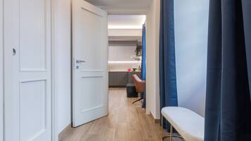 Un pasillo que conduce a una habitación con una cama, una silla y un escritorio.