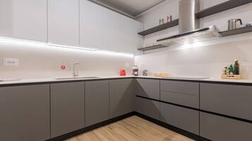 Una cocina moderna con gabinetes grises, una campana extractora de acero inoxidable y piso de madera.