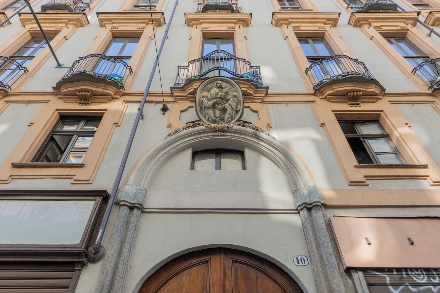 Fachada de edificio con entrada central, varias ventanas y balcones.