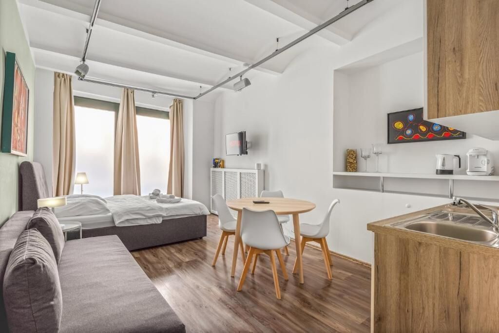 Une chambre d’hôtel moderne équipée d’un lit, d’un canapé, d’une table à manger, de chaises et d’une kitchenette.