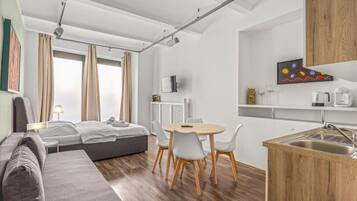 Une chambre d’hôtel moderne équipée d’un lit, d’un canapé, d’une table à manger, de chaises et d’une kitchenette.