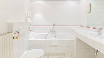A bathroom with a white toilet, a bathtub, and a sink.