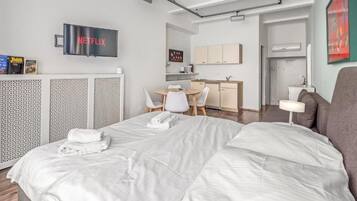 Ein Hotelzimmer mit Bett, Schreibtisch, Stuhl, Fernseher und einer Küchenzeile.