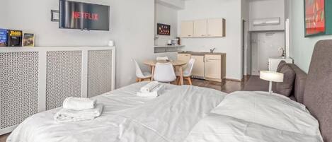 Une chambre d’hôtel équipée d’un lit, d’un bureau, d’une chaise, d’une télévision et d’une kitchenette.