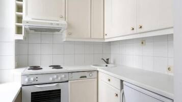 Eine kleine Küche mit weißen Schränken, einem Herd und einem Kühlschrank.