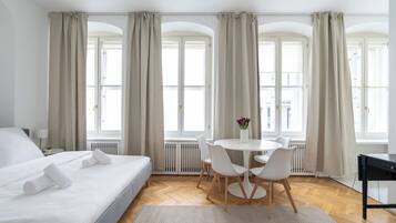 Ein Hotelzimmer mit einem Bett, einem runden Tisch mit Stühlen und großen Fenstern mit Vorhängen.