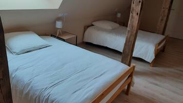 Une chambre avec deux lits en bois, une table de chevet avec une lampe et une lucarne.