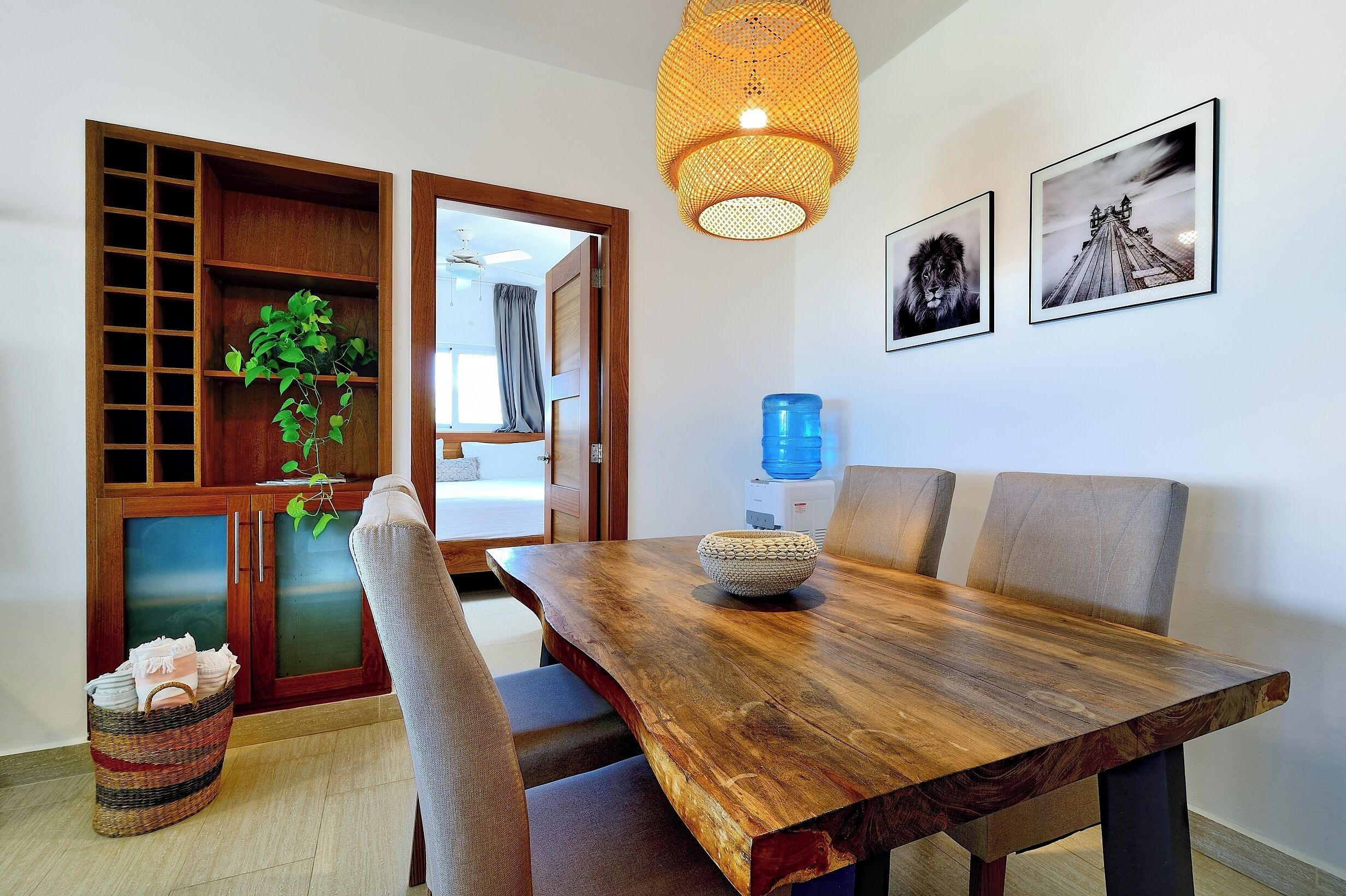 Un espace repas comprenant une table en bois, des chaises, un luminaire suspendu et un distributeur d’eau.