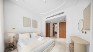 A modern hotel bedroom with a large bed, bedside tables, a mirror, and a bathroom visible through an open door. - StayShort - Luxury 1-Bedroom Apartment at Ellington Beach House, Palm Jumeirah (Palm Jumeirah)