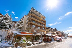 Un edificio de varios pisos con balcones, un restaurante y un estacionamiento.
