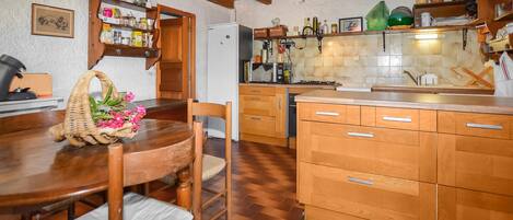 A kitchen with wooden cabinets, a dining table with chairs, and a microwave.