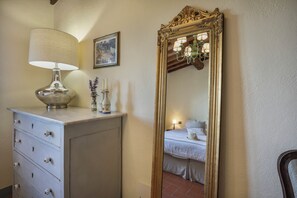A room with a dresser, a lamp, a mirror, and a bed. - Casa Poggio in Badia in the Chianti Shire (Toscana)