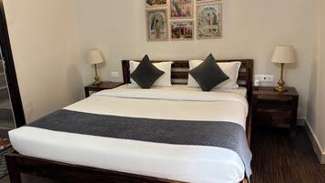A neatly made bed with a dark quilt, two bedside lamps, and a wall with framed pictures.