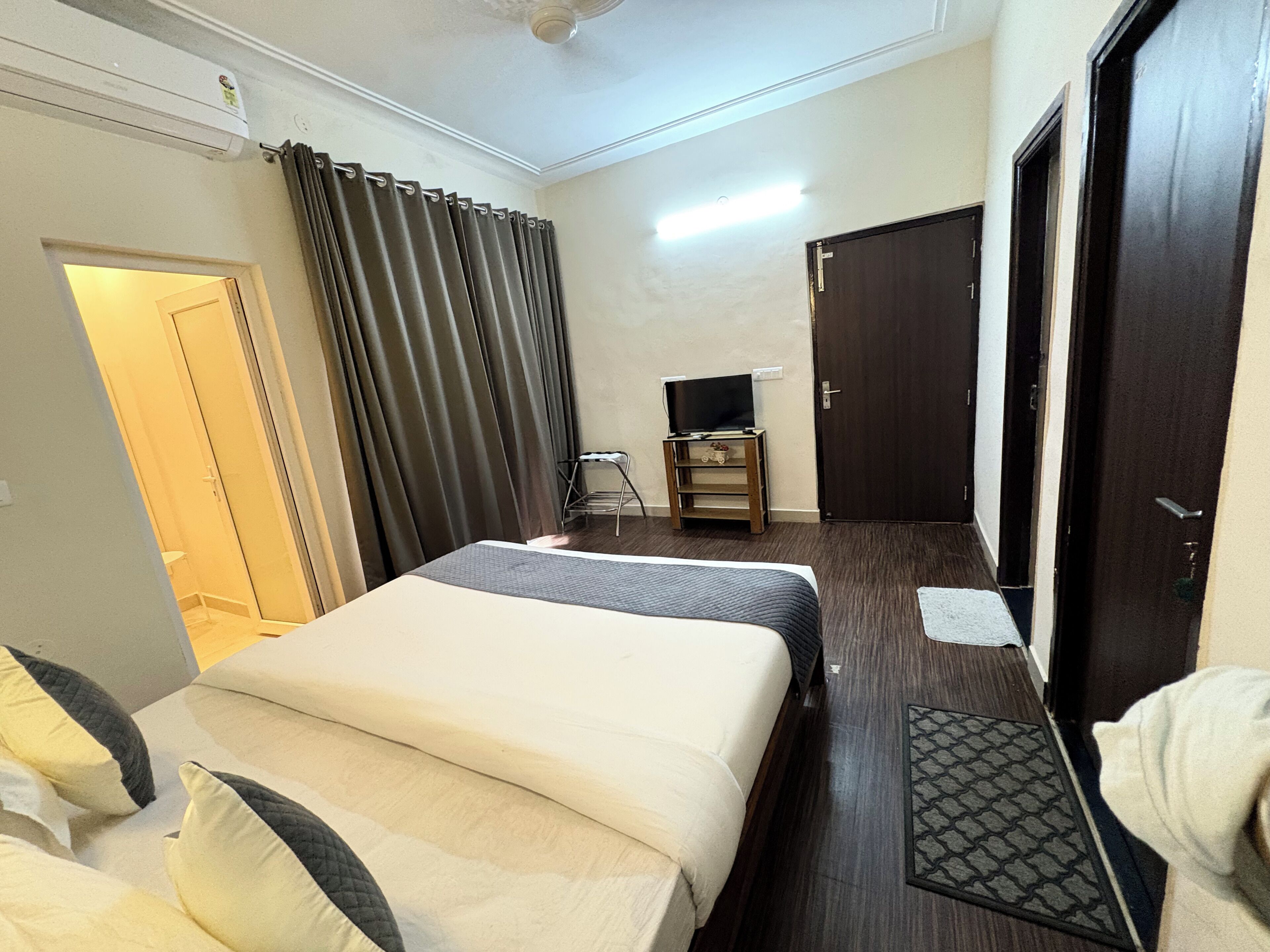A hotel room with two beds, a television on a small table, and a door.
