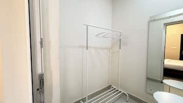 A room with a white metal drying rack, a small white table, and a mirror on the wall.