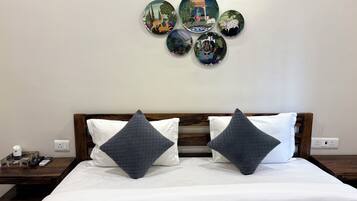 Camera d'albergo con un letto, due cuscini, un comodino e una parete decorata con piatti.