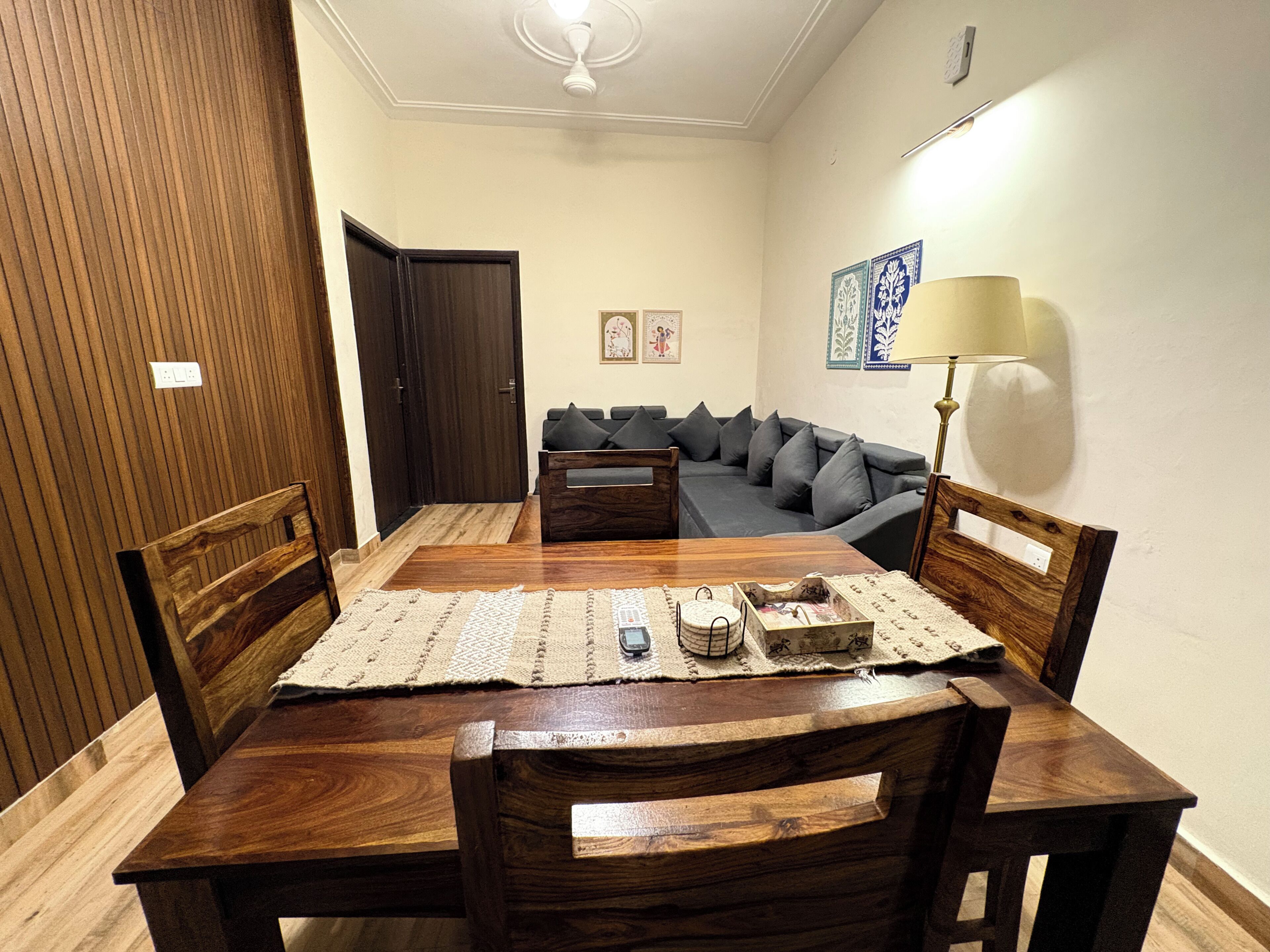 A dining area with a wooden table, chairs, a sofa, and a lamp.