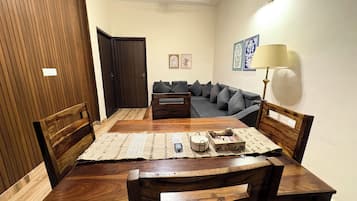 A dining area with a wooden table, chairs, a sofa, and a lamp.
