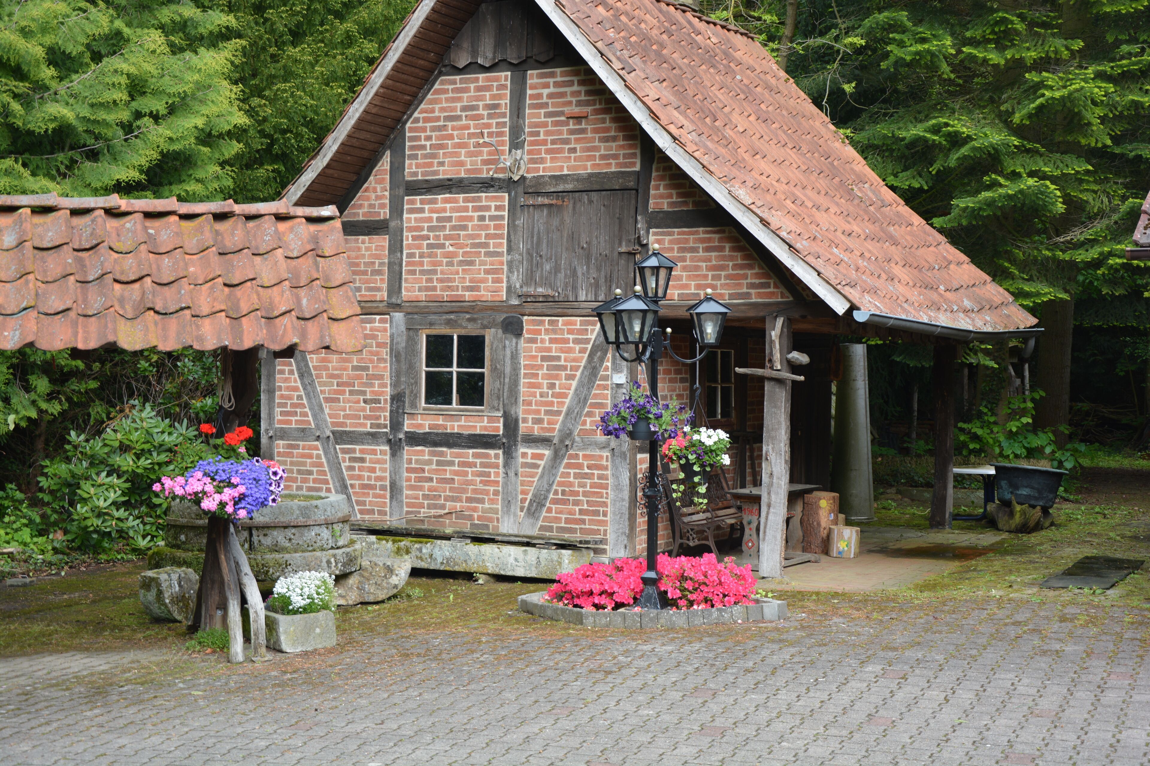 A traditional half-timbered house with a tiled roof, a small porch, and hanging flower baskets.