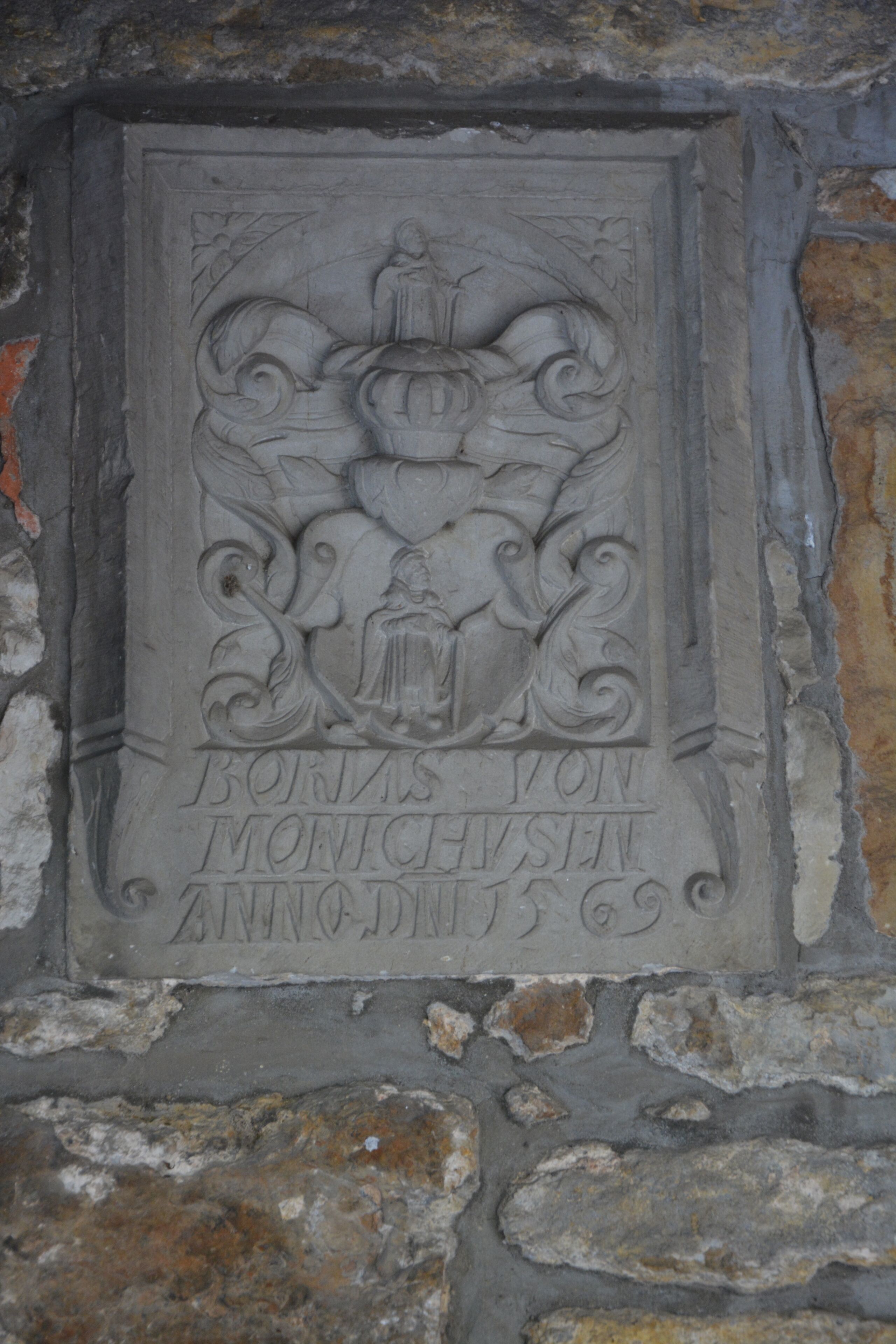 Una lápida de piedra con texto grabado y un escudo de armas.