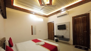A hotel room with a bed, a television, a mirror, and a wooden ceiling.