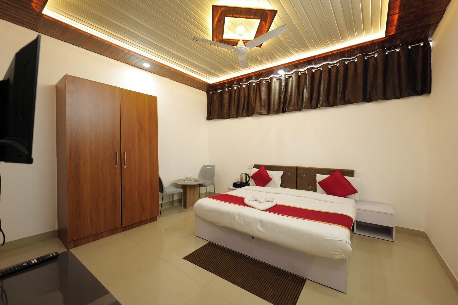 A bedroom with a bed, a wardrobe, a desk, and a television.