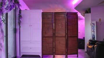 A room with a white wardrobe, a wooden cabinet, a sofa, and a glass cabinet.