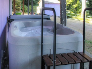 A hot tub with a metal ladder and wooden steps. - Lavender Oceanview Retreat (Bremerton)