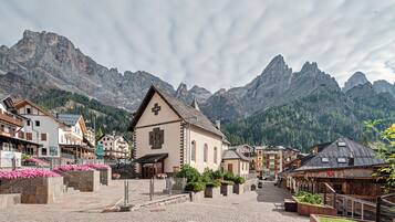 Ein Stadtplatz mit Kirche, Kopfsteinpflaster und Blick auf die Berge.