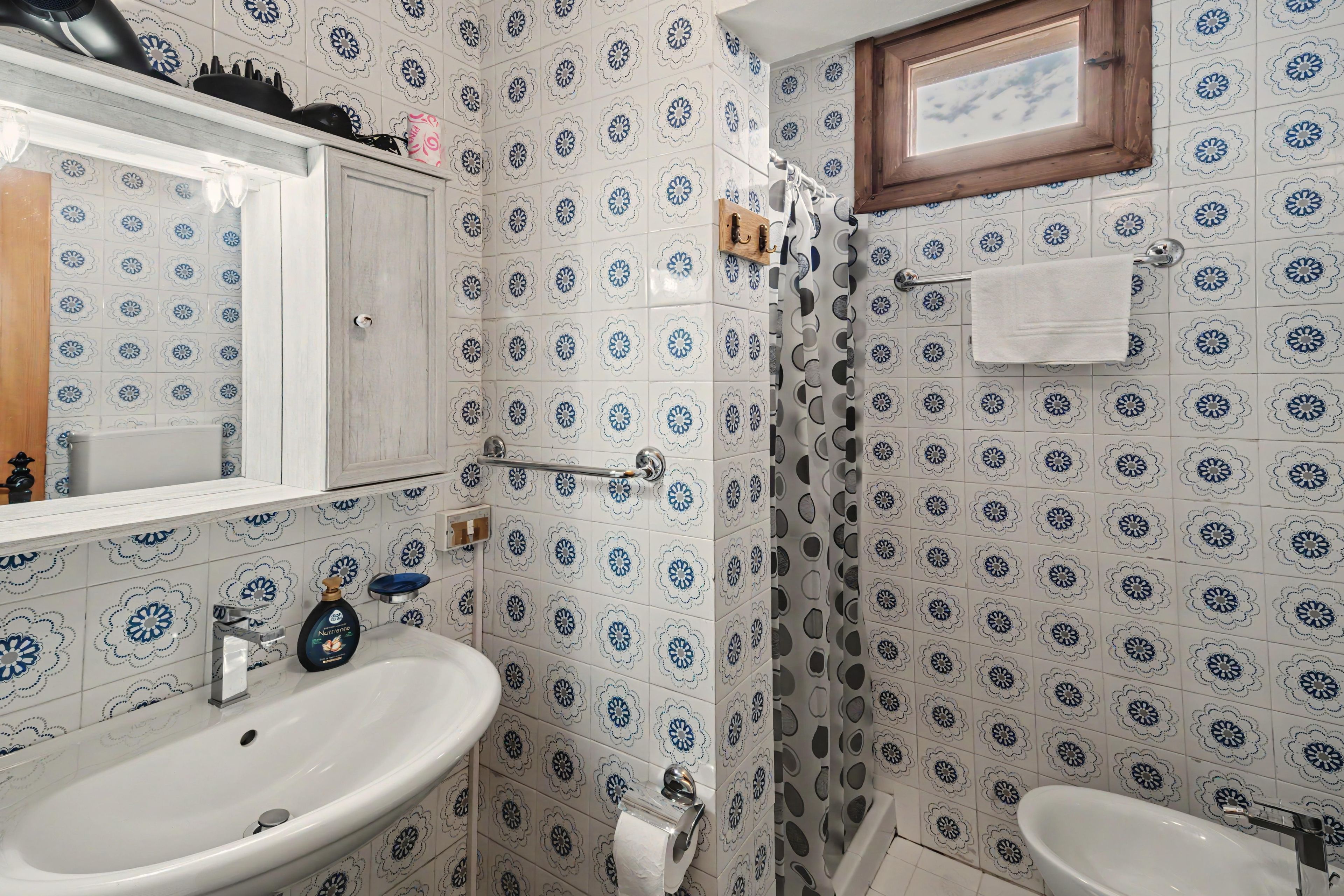 A bathroom with a white sink, a mirror, and a shower with a wooden door.