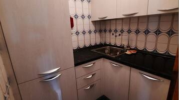 Una cucina con mobili chiari, un piano di lavoro nero e un backsplash decorato.