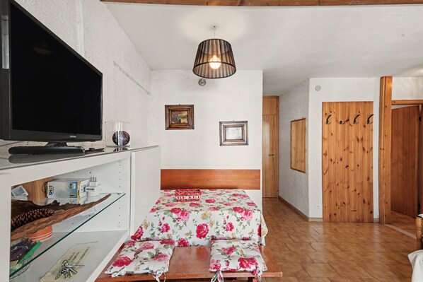 A room with a bed, a television, and a wooden door.