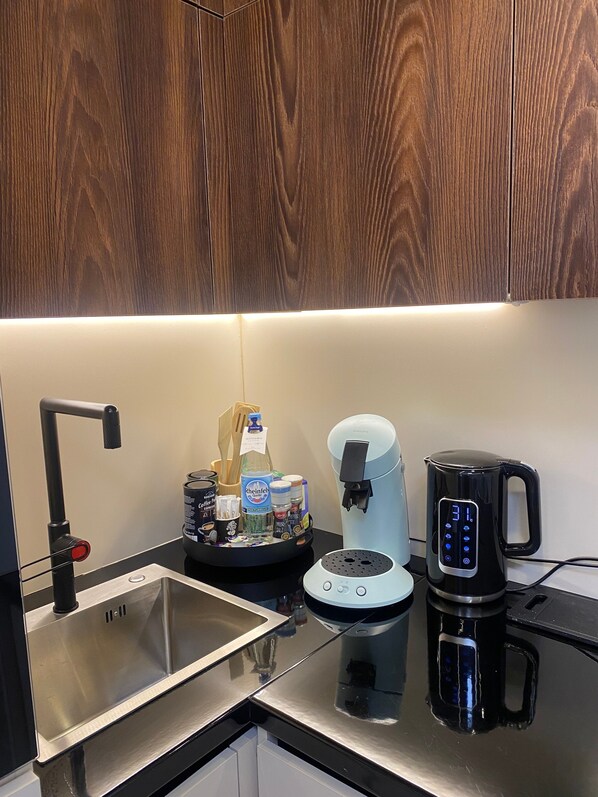 A modern kitchen with a stainless steel sink, a coffee maker, and a kettle.