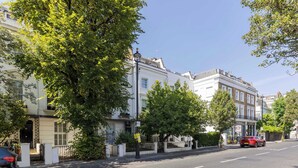 Una strada fiancheggiata da edifici tradizionali, cielo sereno e un'auto parcheggiata.