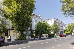 Eine Straße gesäumt von traditionellen Gebäuden, ein klarer Himmel und ein geparktes Auto.