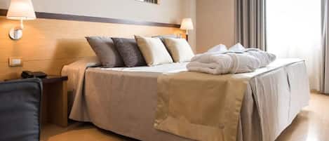 A hotel room with a bed, bedside lamps, a telephone, and a mirror on the wall.