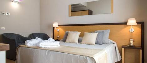 A hotel room with a bed, two bedside tables, a chair, and a mirror on the wall.