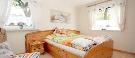 Un dormitorio acogedor con una cama de madera, una mesita de noche, una silla y una ventana con cortinas.