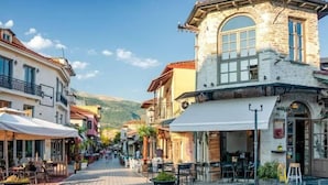 A street with buildings, outdoor seating, and a clear sky.