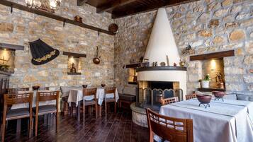 Um interior rústico com paredes de pedra, lareira, móveis de madeira e um candelabro.