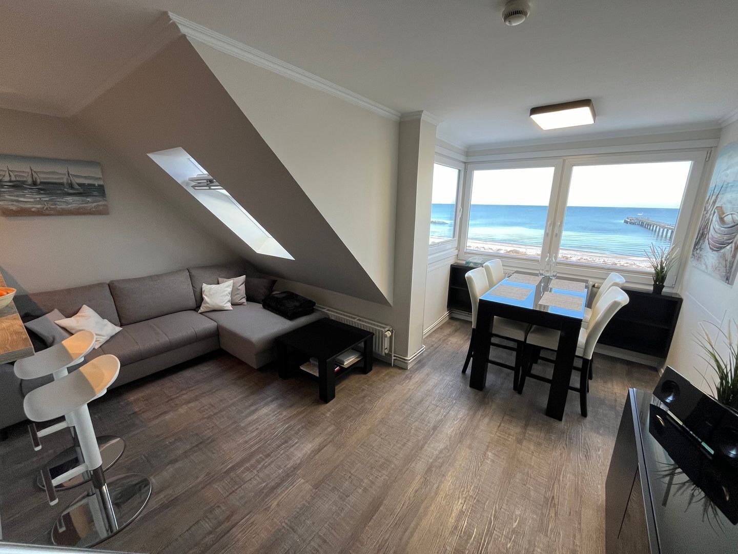 Una sala de estar moderna con un sofá, una mesa de comedor y vistas al océano.
