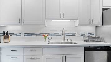 A modern kitchen with white cabinets, a stainless steel sink, and a dishwasher.