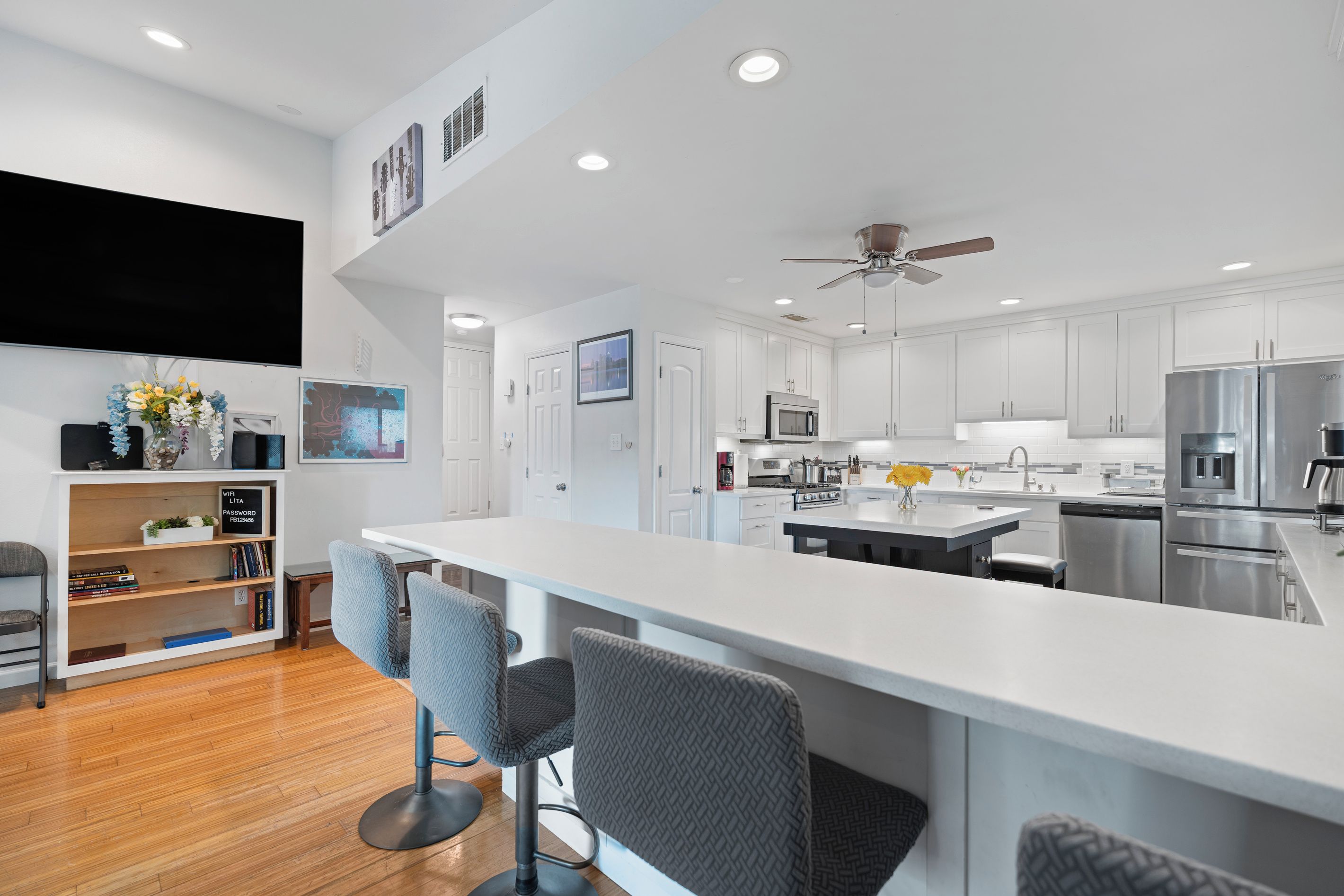 A modern kitchen with white cabinetry, a central island, and a built-in oven.