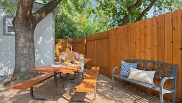 A picnic setup with a wooden table, benches, and a bench with cushions.