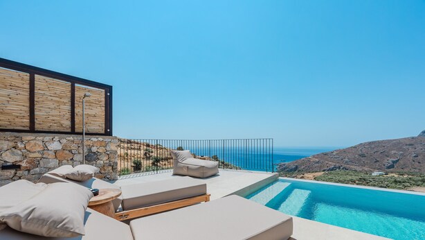 A poolside area with lounge chairs and a stone wall. - Metatulia Villa 7 – Private Pool, Jacuzzi & Views (Plakias)